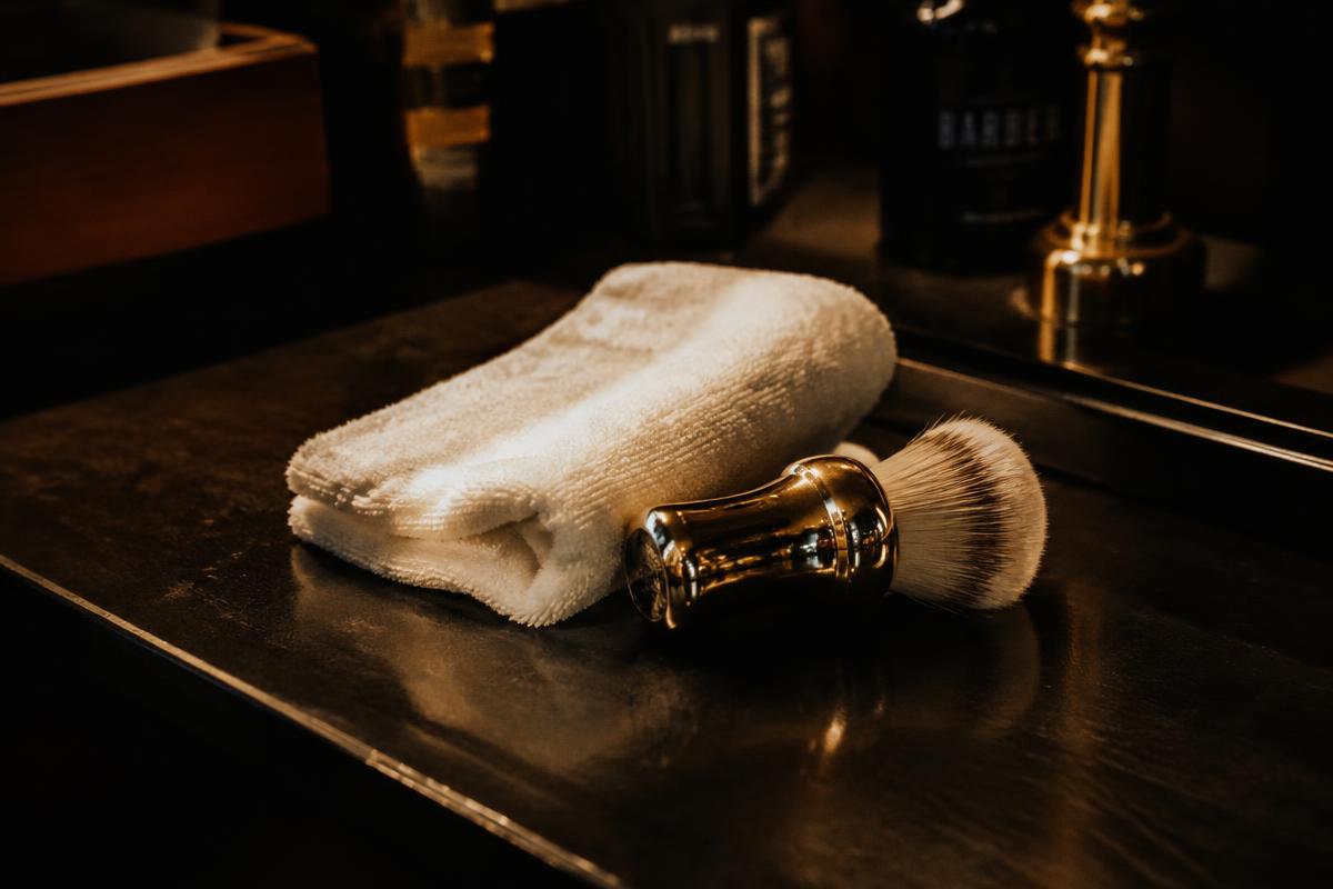 Hot towel and shaving brush on a dark counter